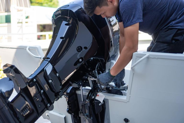 Mechanic is installing speed boat engine , a new engine on an aluminum boat.