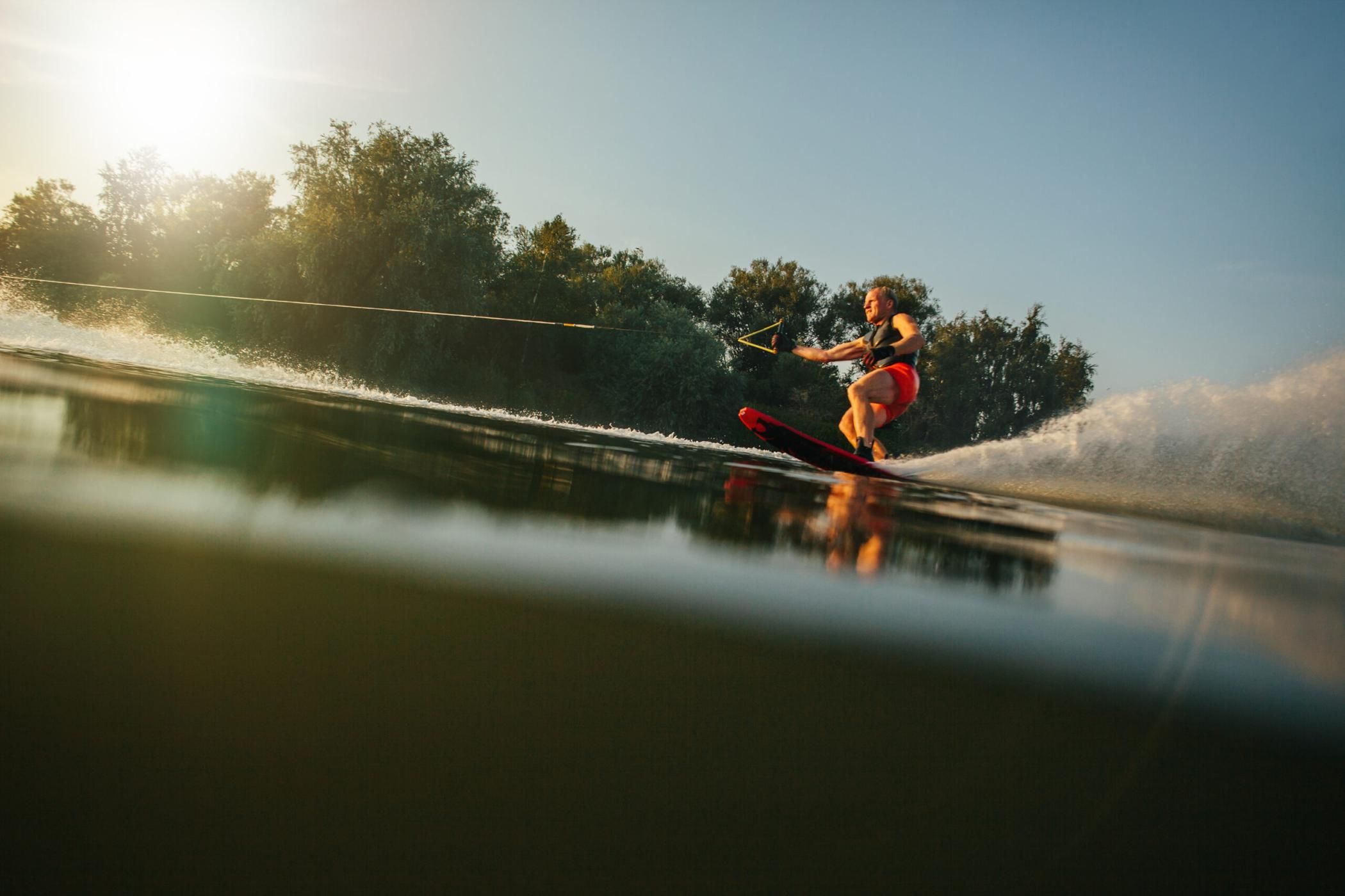 Athlete water skiing behind a boat. Man wakeboarding on a lake.