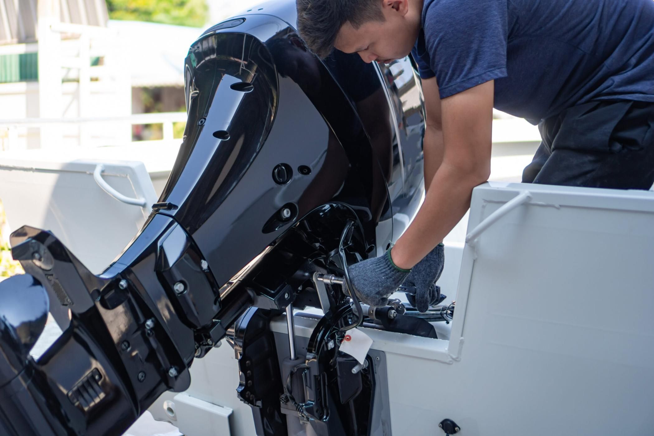 Mechanic is installing speed boat engine , a new engine on an aluminum boat.